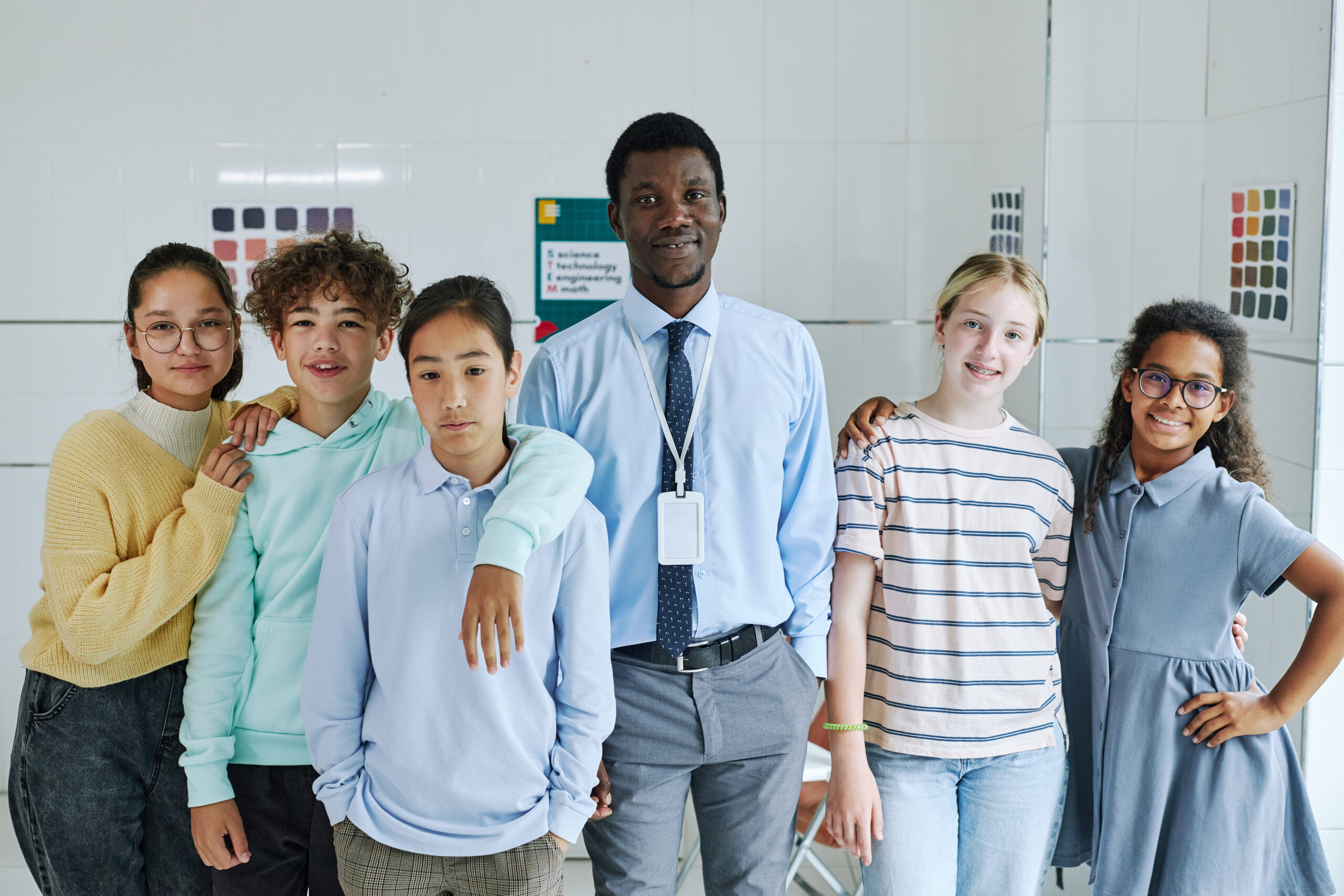 Diverse group of children with young male teacher looking at camera in mental health center