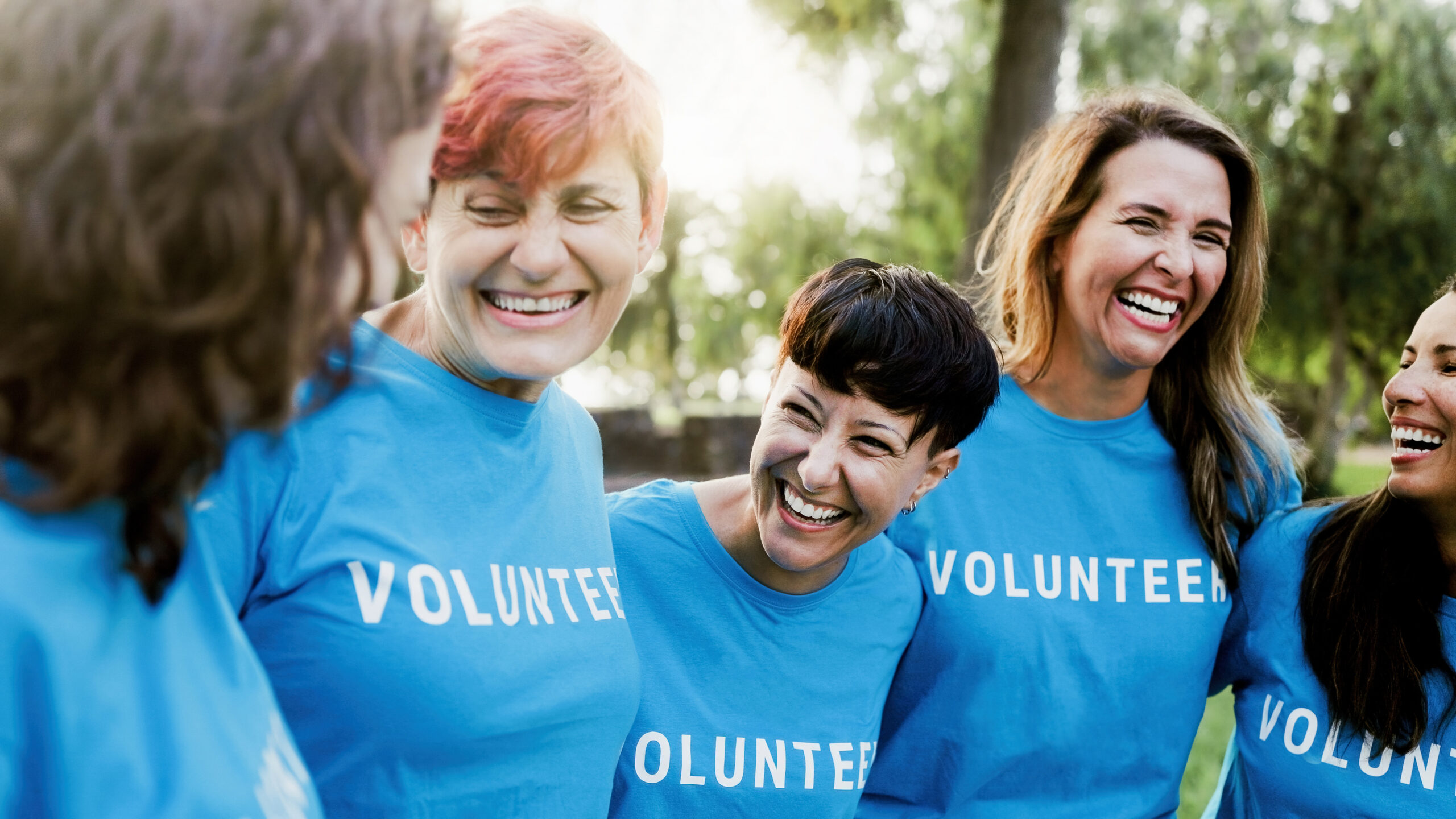 Diverse group of volunteer people celebrating together outdoors. Women teamwork and charity support concept.